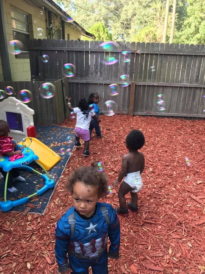 A group of children are playing with soap bubbles in a backyard.