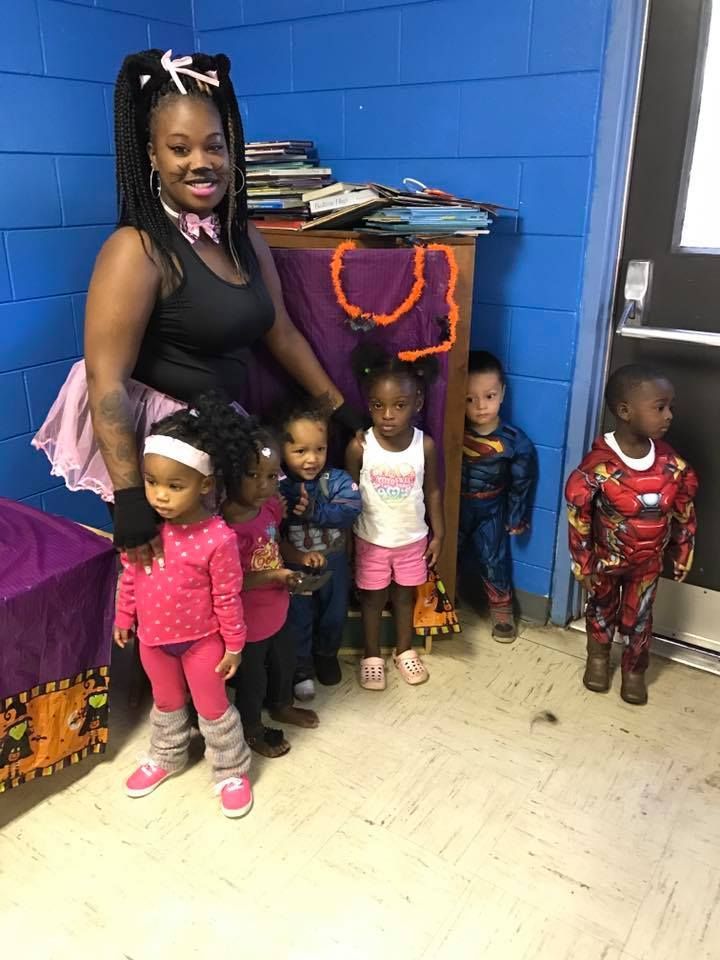 A woman is standing next to a group of children dressed in costumes.