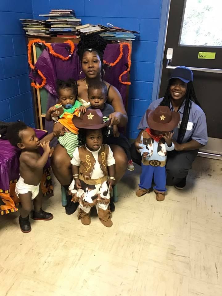 A woman is sitting on a chair next to a group of children dressed in costumes.