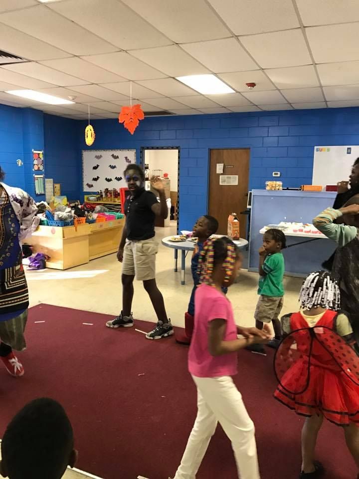 A group of children are dancing in a room with blue walls