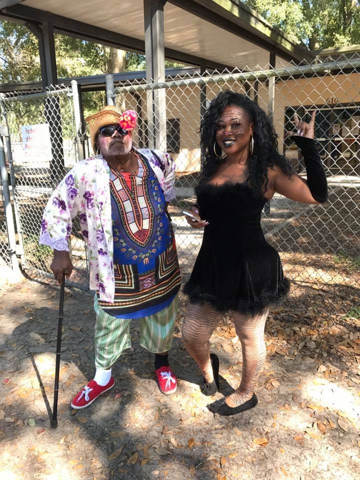 A man and a woman are standing next to each other in front of a chain link fence.