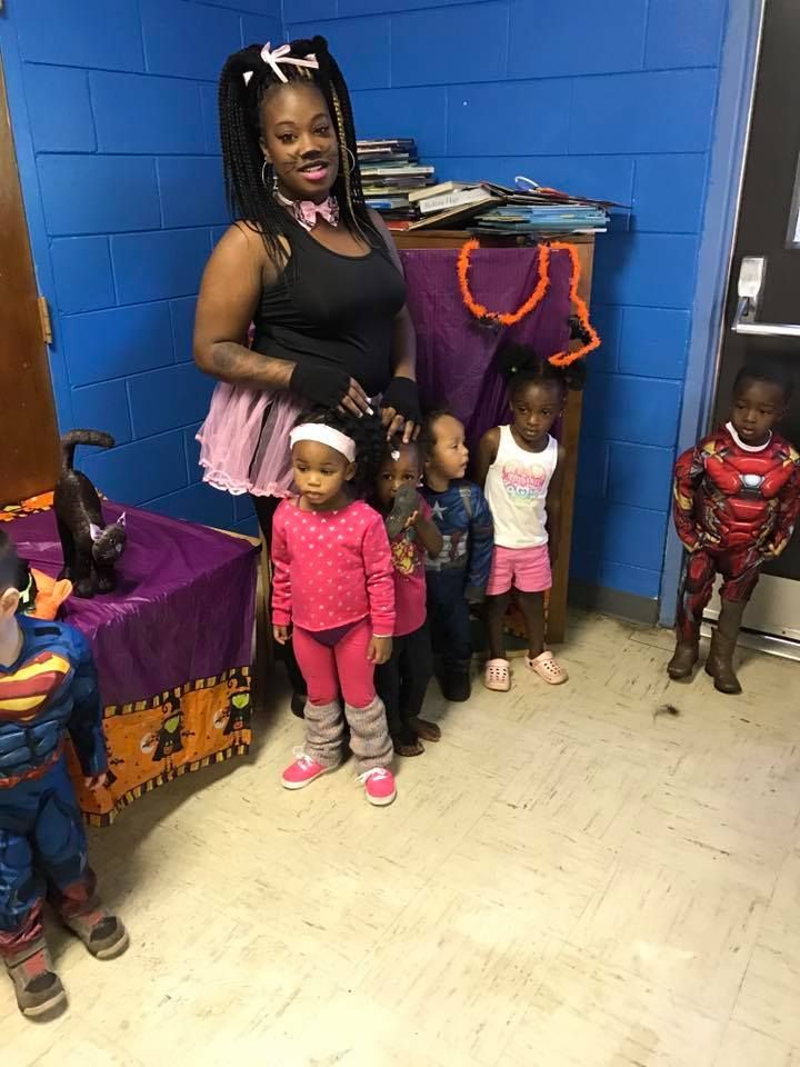A woman is standing next to a group of children in costumes.