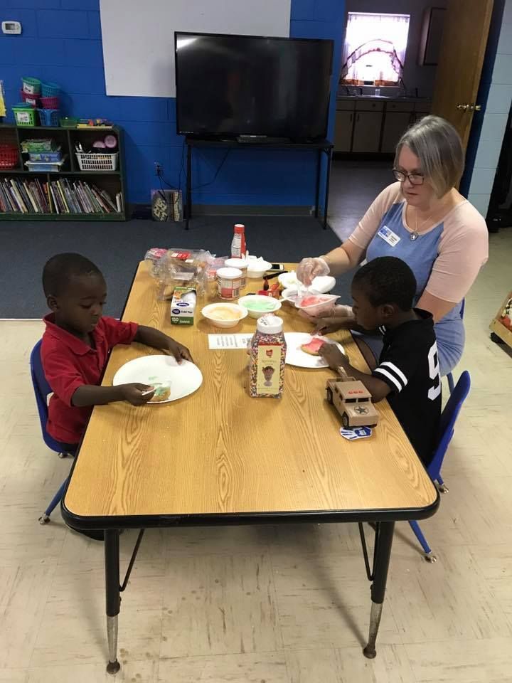 A woman is sitting at a table with two children.