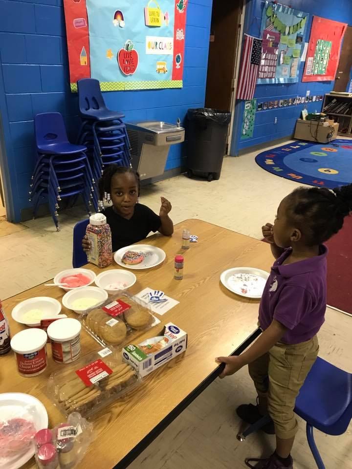 Two young girls are sitting at a table with plates of food.