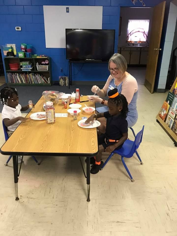 A woman and two children are sitting at a table eating food.