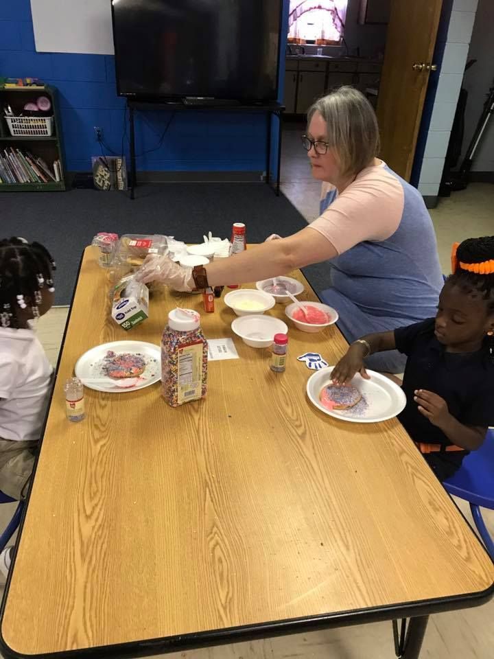 A woman is sitting at a table with two children.
