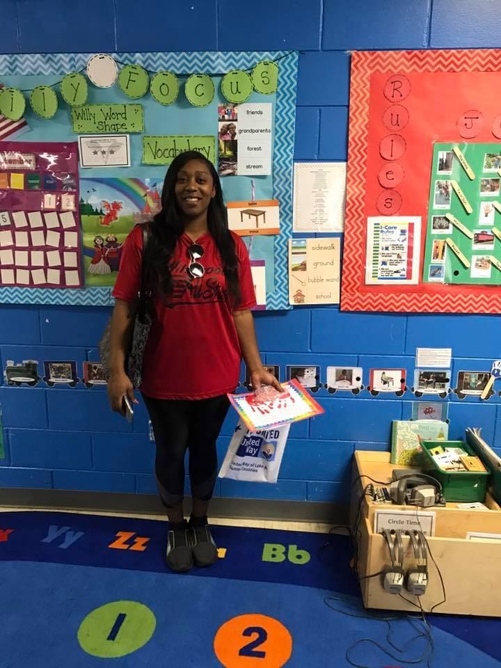 A woman in a red shirt is standing in front of a bulletin board