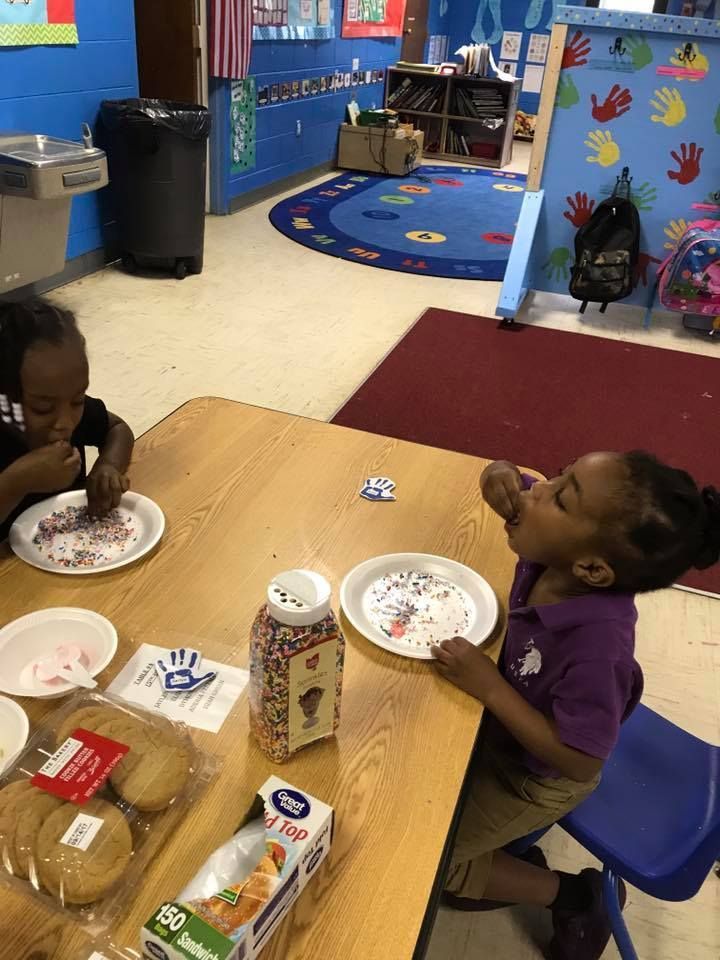 Two children are sitting at a table eating food.