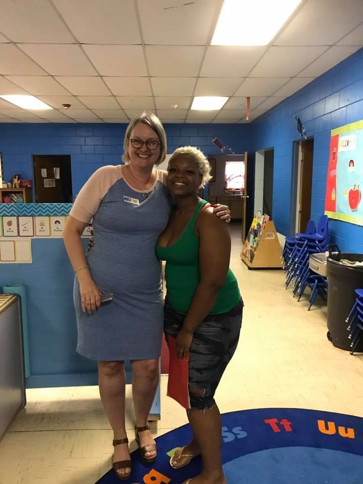 Two women are posing for a picture in a room with blue walls.