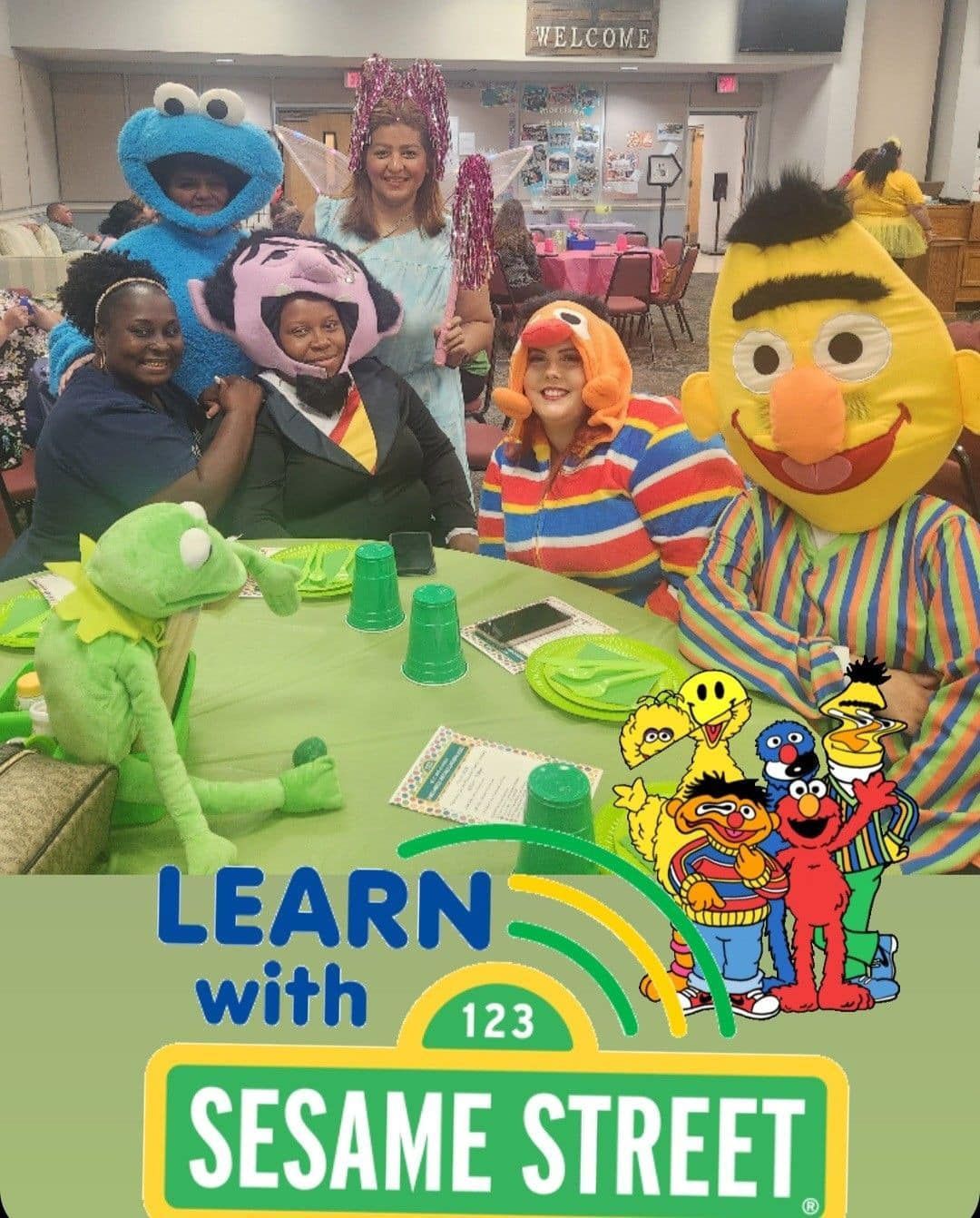 A group of people are sitting at a table with sesame street characters.