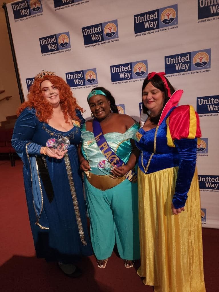 Three women dressed as princesses are posing for a picture.