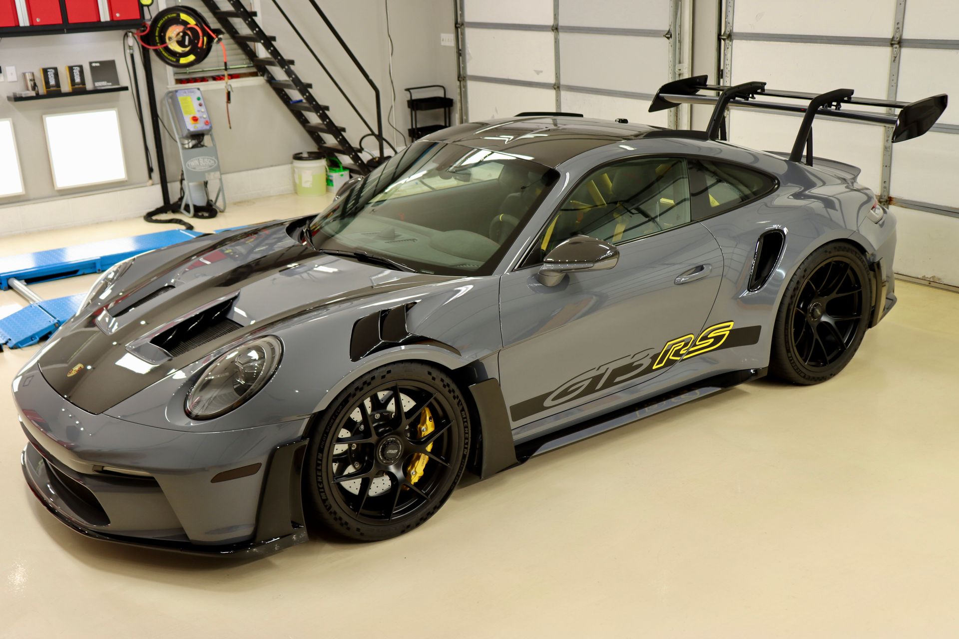 Gray Porsche 911 GT3 RS parked inside a garage, featuring black accents and a large rear wing.