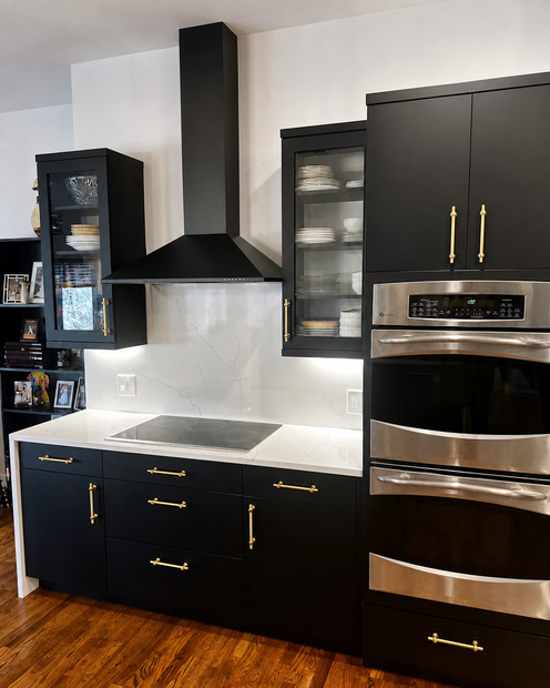 Modern kitchen with black cabinets, stainless steel ovens, and a black range hood