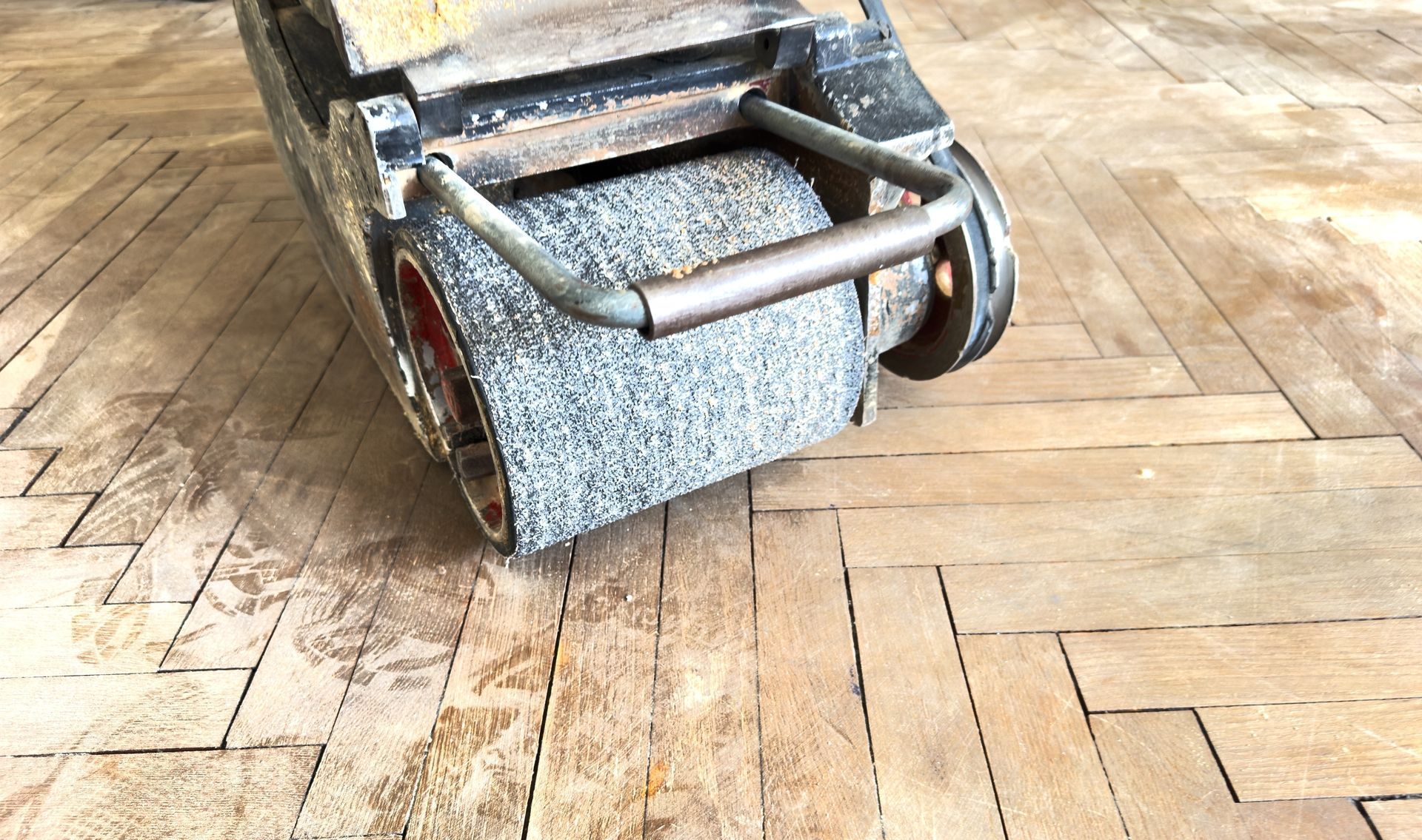 Close-up of a wheelchair’s front wheels on a wooden floor, with a blue patterned footrest.
