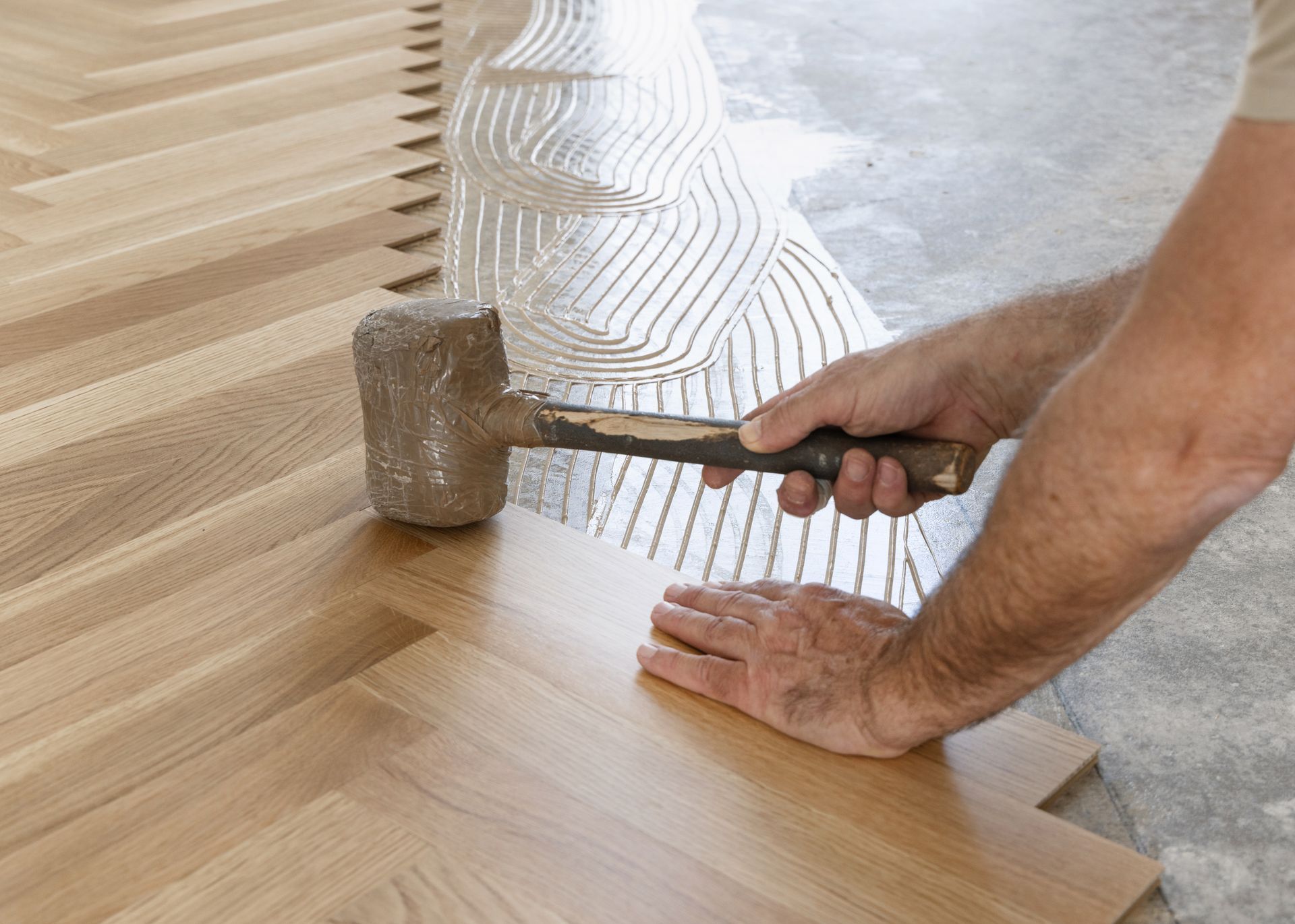 Person using a mallet to tap wooden flooring into place during installation