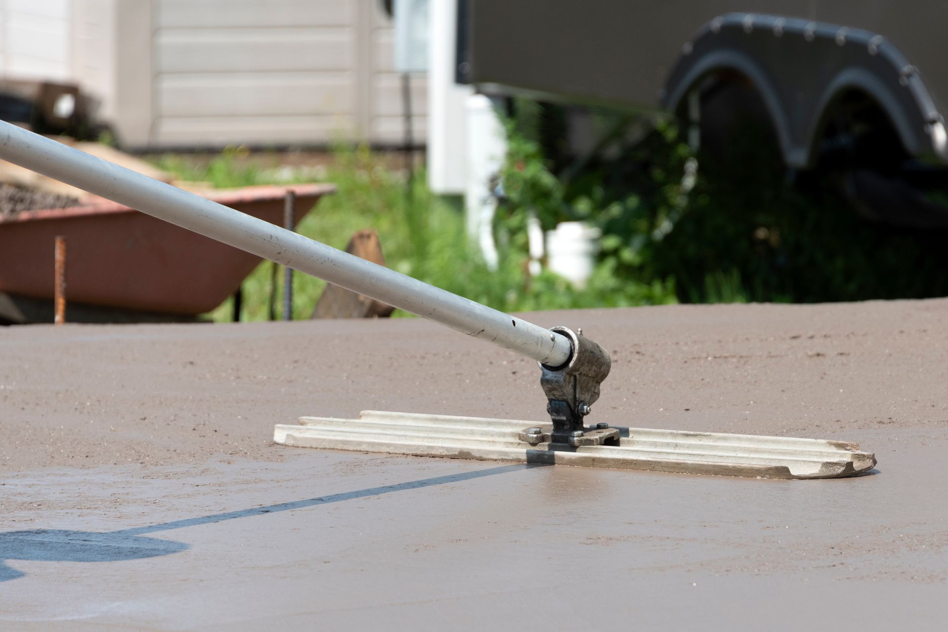 A metal tool rests on a beige tabletop beside a small puddle outdoors.