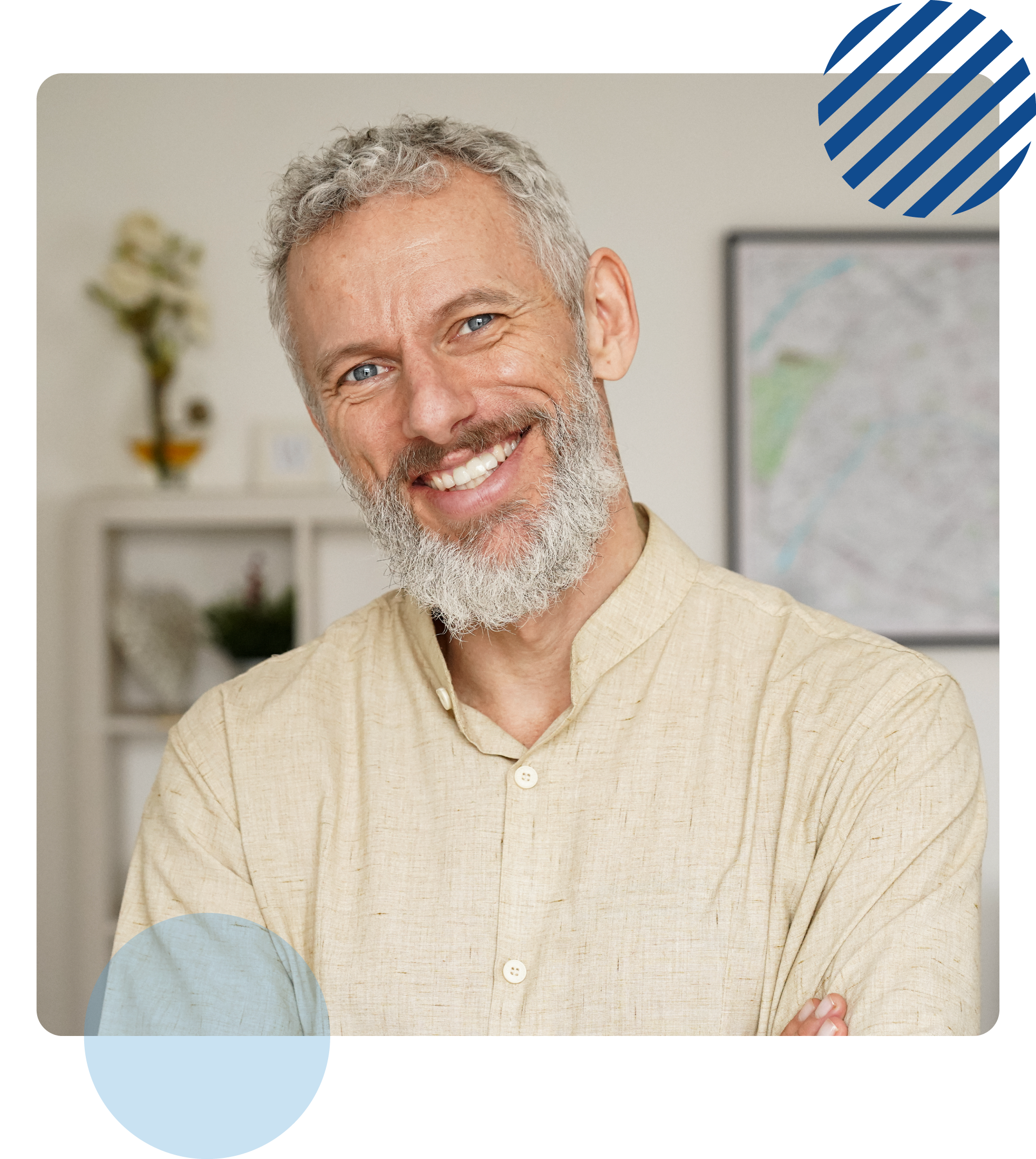 Man with gray beard smiles, arms crossed, in a light-colored shirt. Blurred office backdrop.