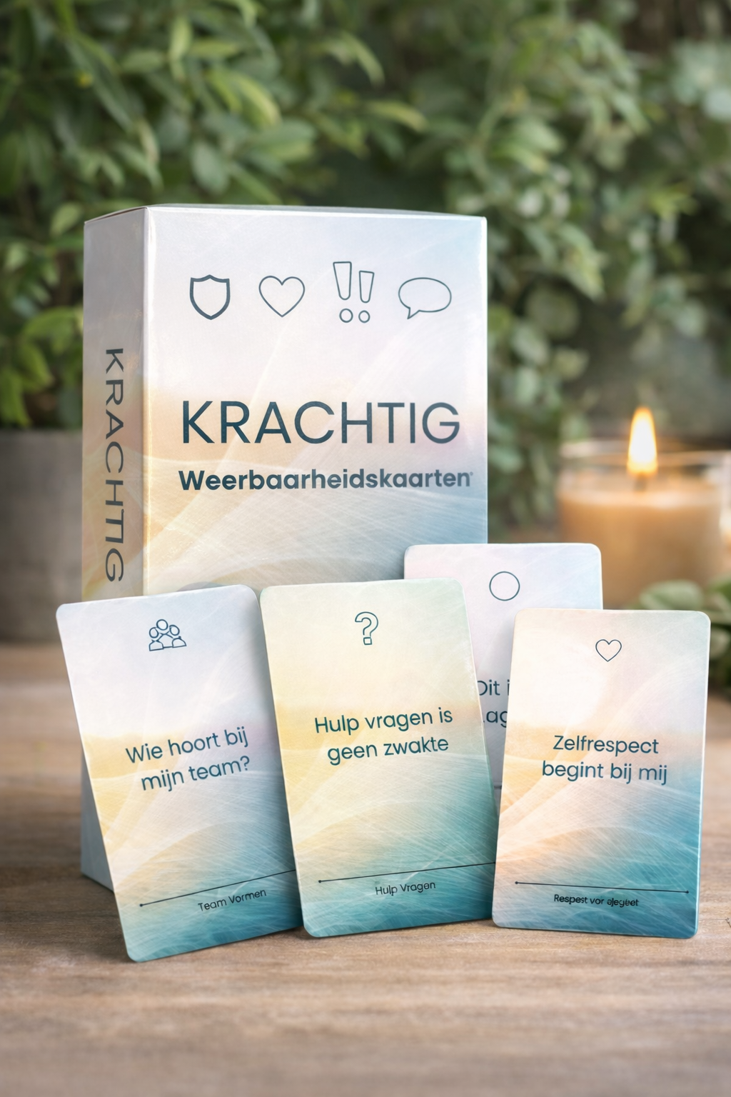 Krachtige mindfulness-kaartenset met drie pastelkleurige kaarten op een houten tafel en een brandende kaars op de achtergrond.