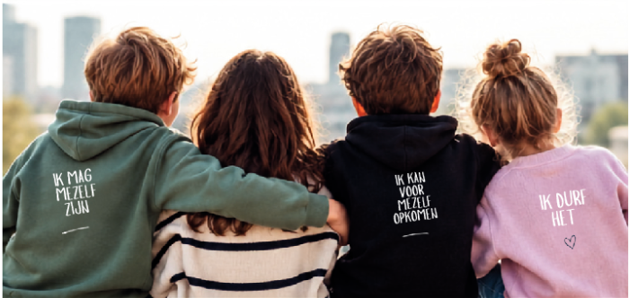 Vier kinderen staan dicht bij elkaar tegen een witte achtergrond, gekleed in gezellige herfstkleding, en kijken naar de camera.