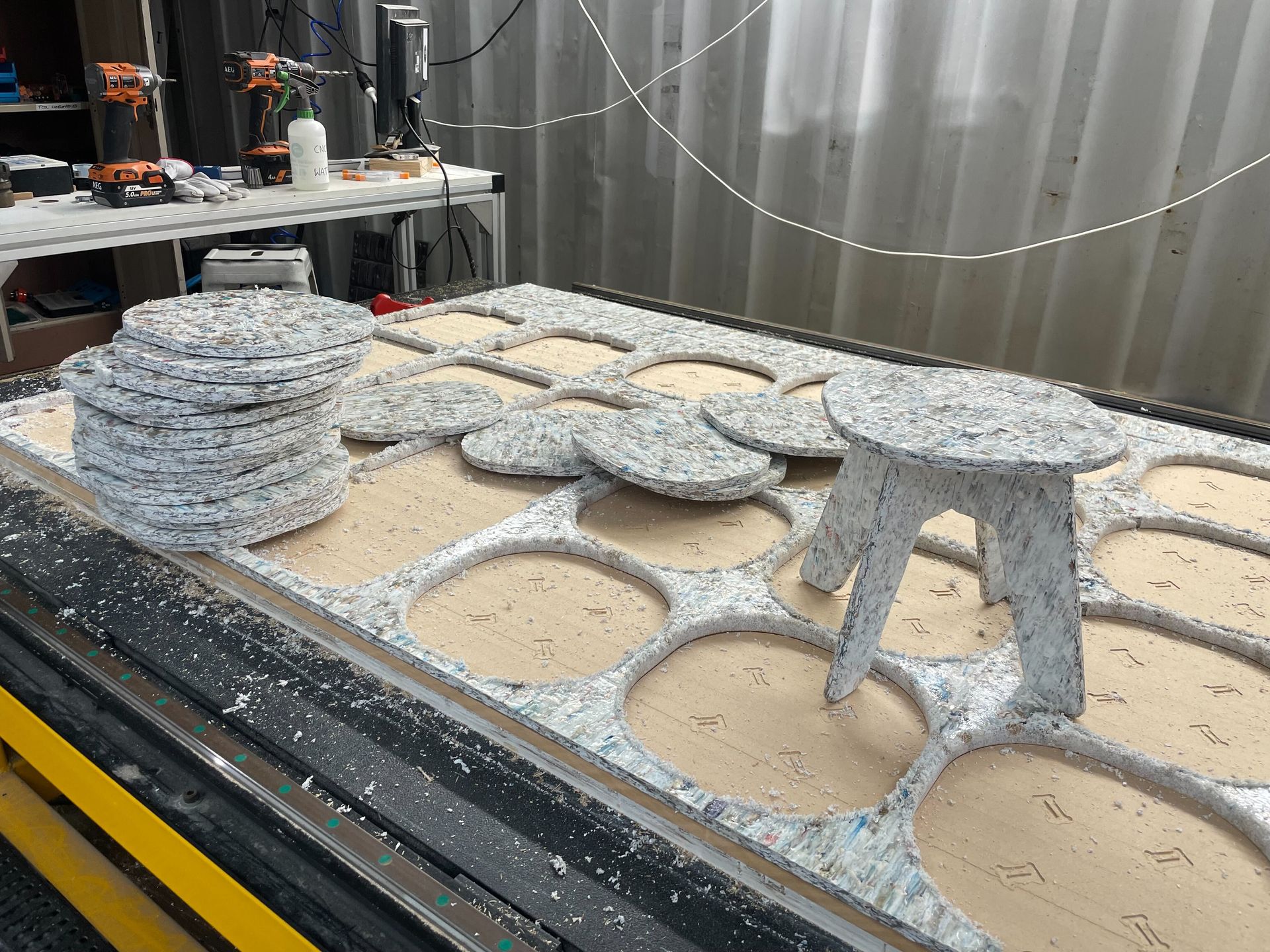 A workshop table with a partially built saveBOARD stool and CNC cut-out shapes.