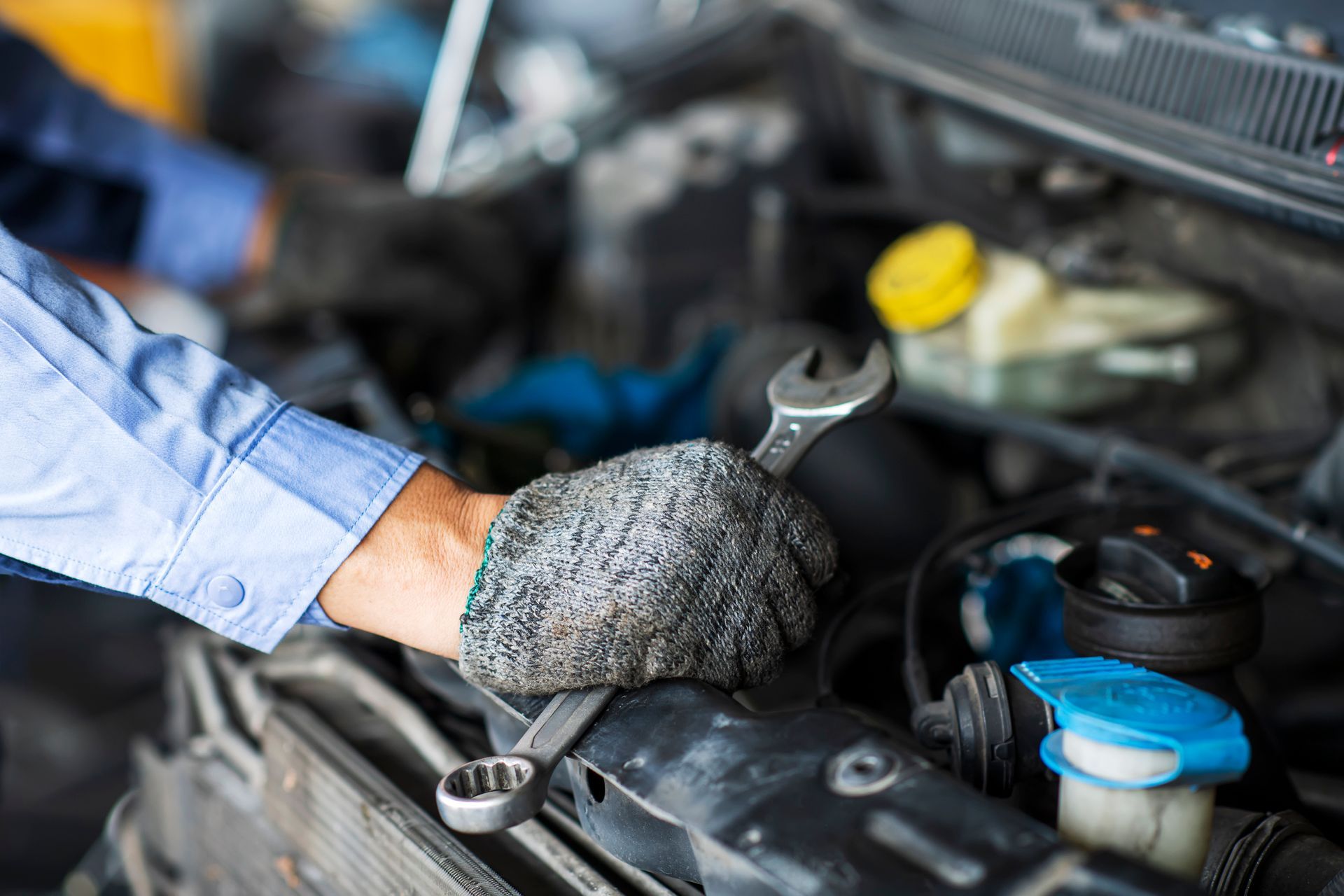 A mechanic is working on a car with a wrench.