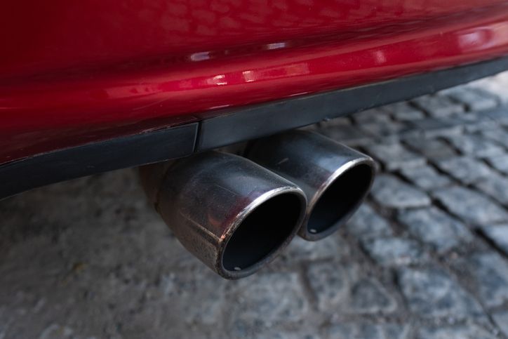 A man is working on the exhaust pipe of a car.