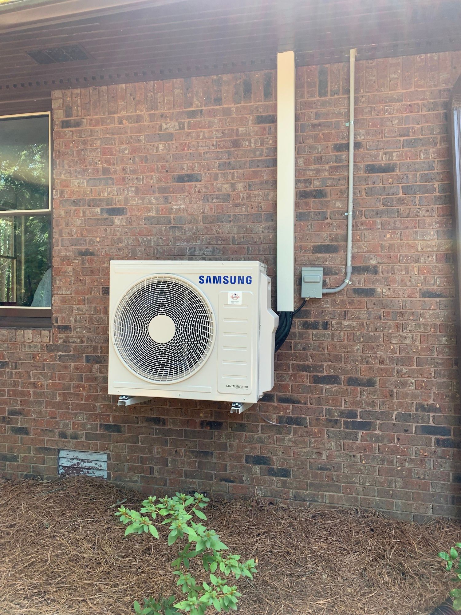 A samsung air conditioner is mounted on the side of a brick building.