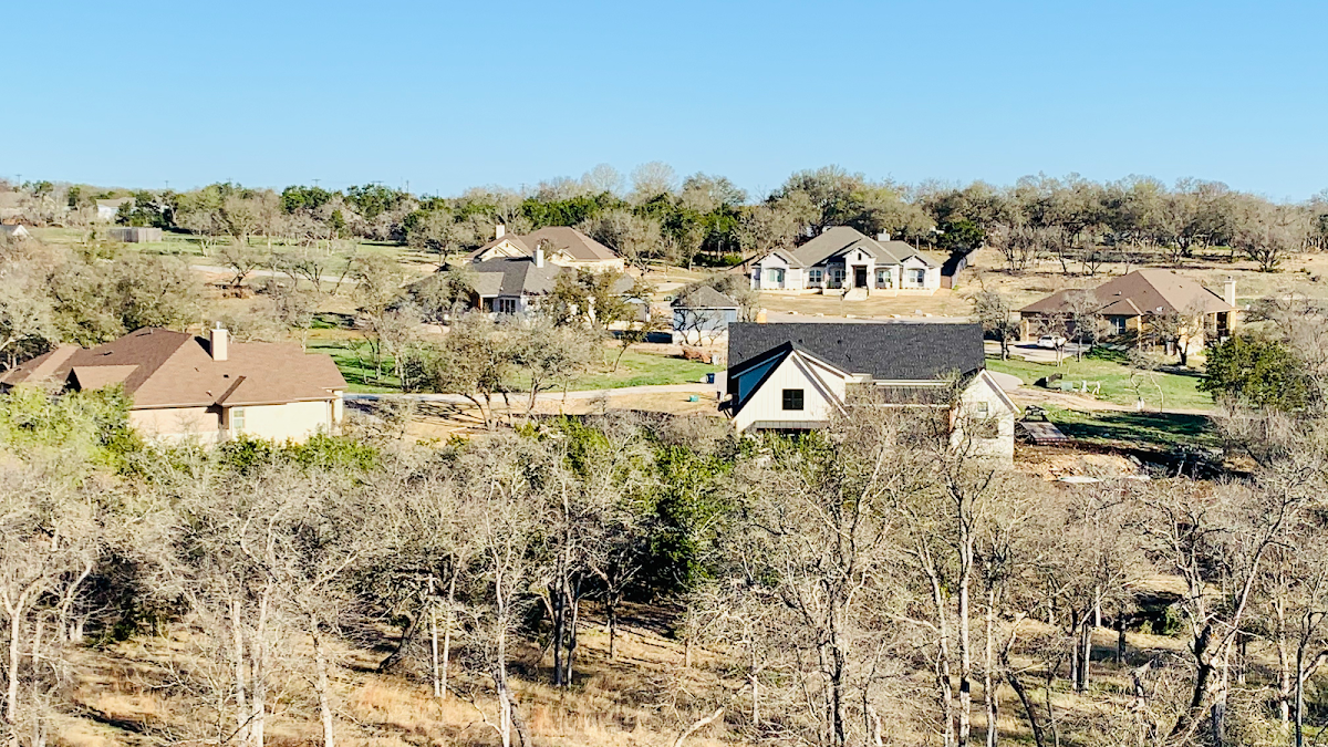 A group of houses are sitting on top of a hill surrounded by trees.