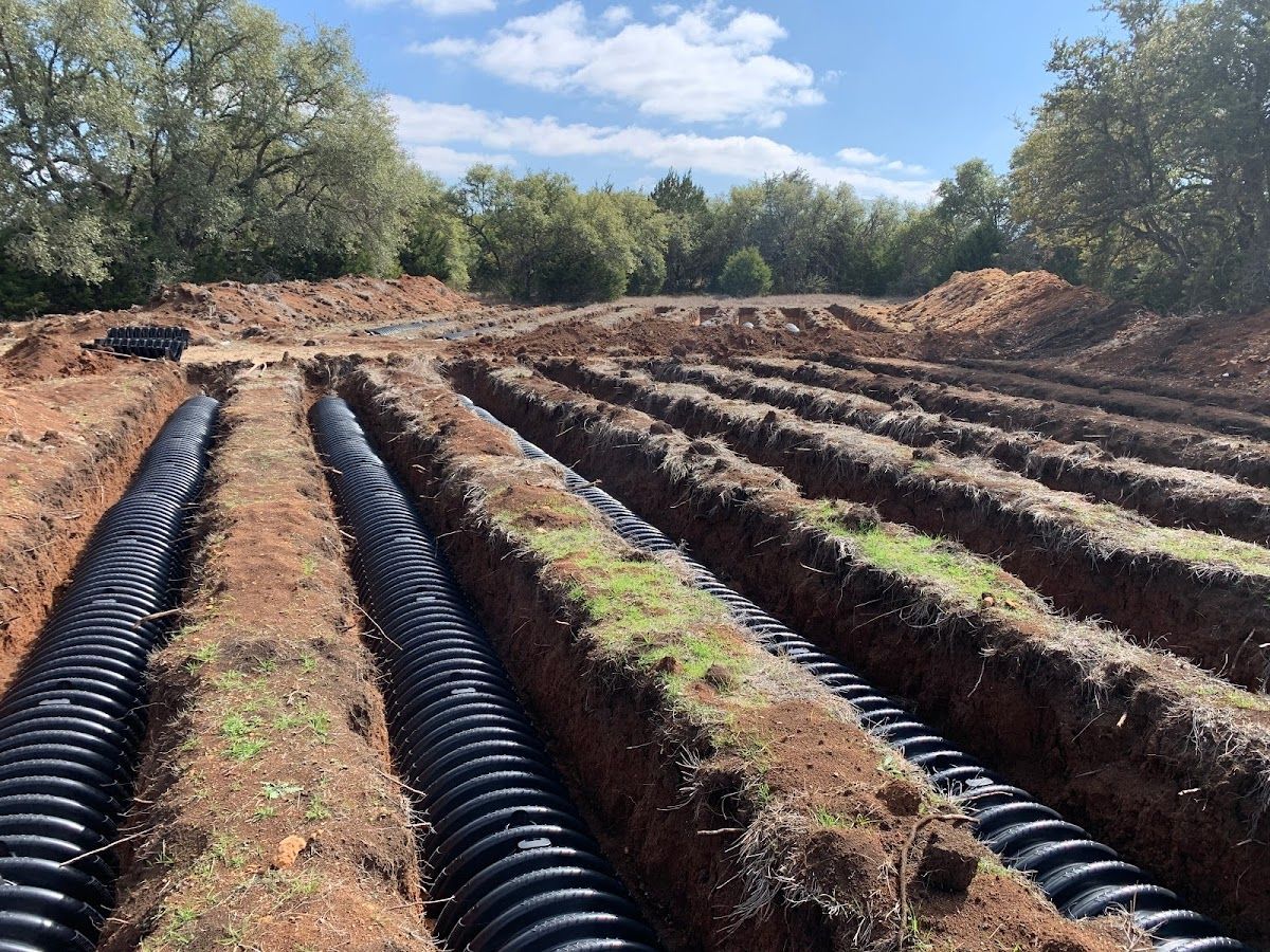 A row of black pipes are laying in the dirt in a field.