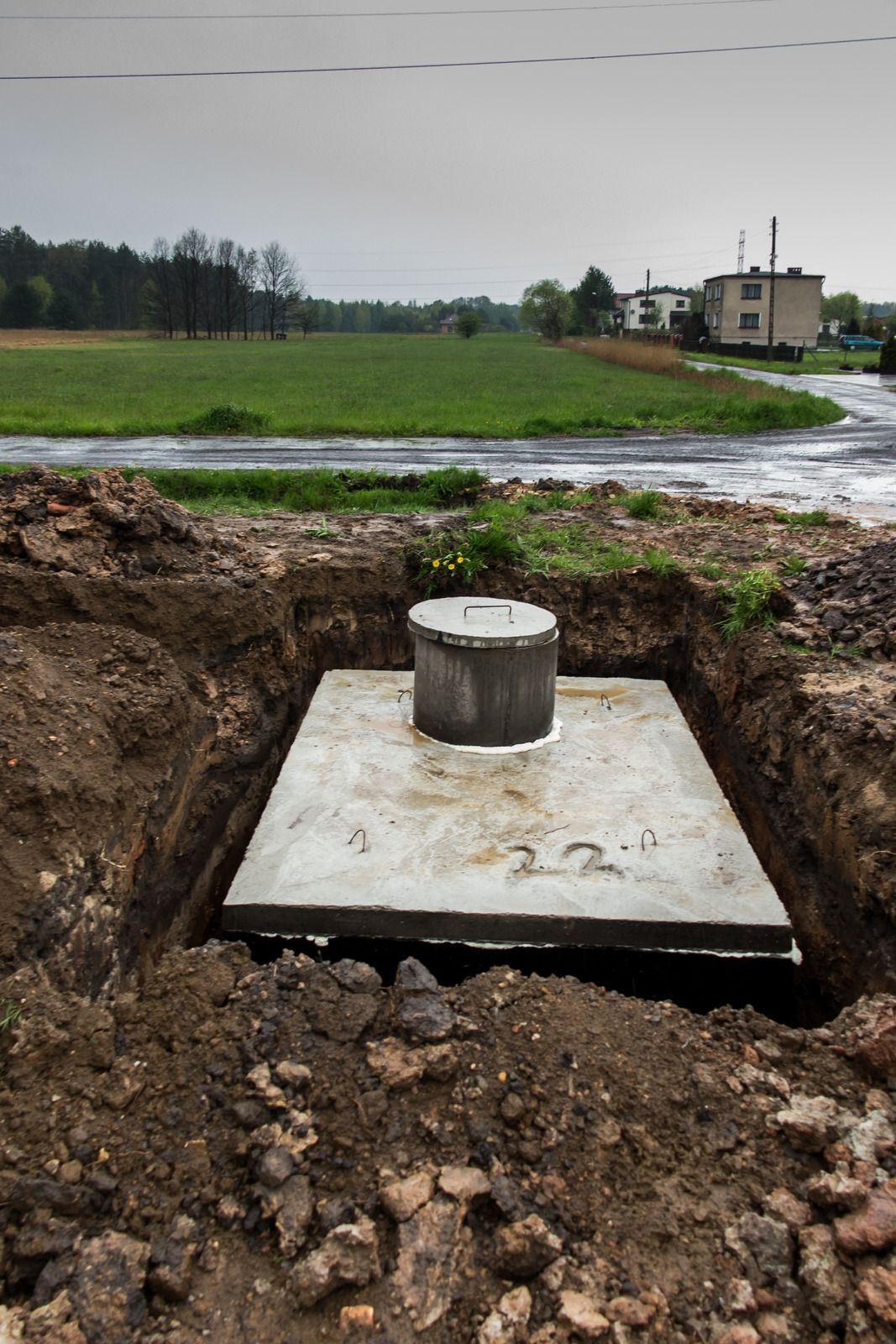 A concrete septic tank is being built in a hole in the ground.