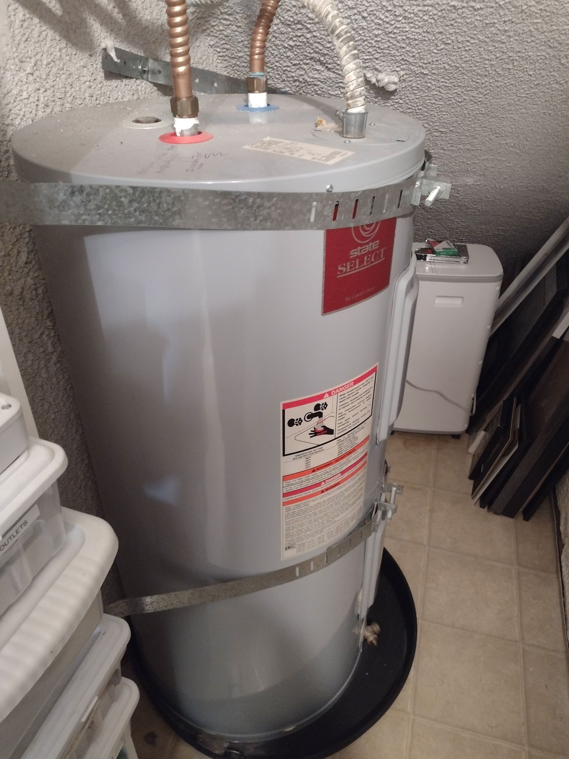 A white water heater is sitting on the floor in a room.