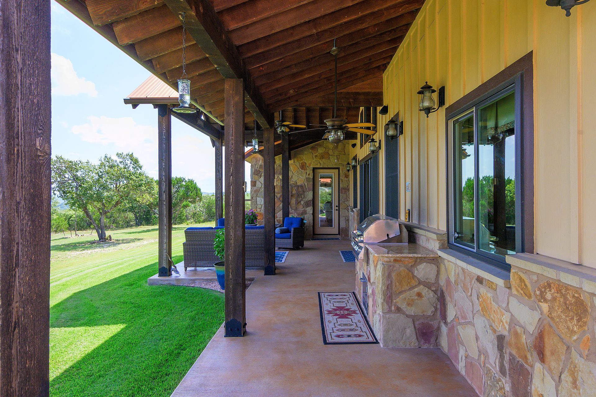 A large porch with a wooden roof and a lot of windows on the side of a house.
