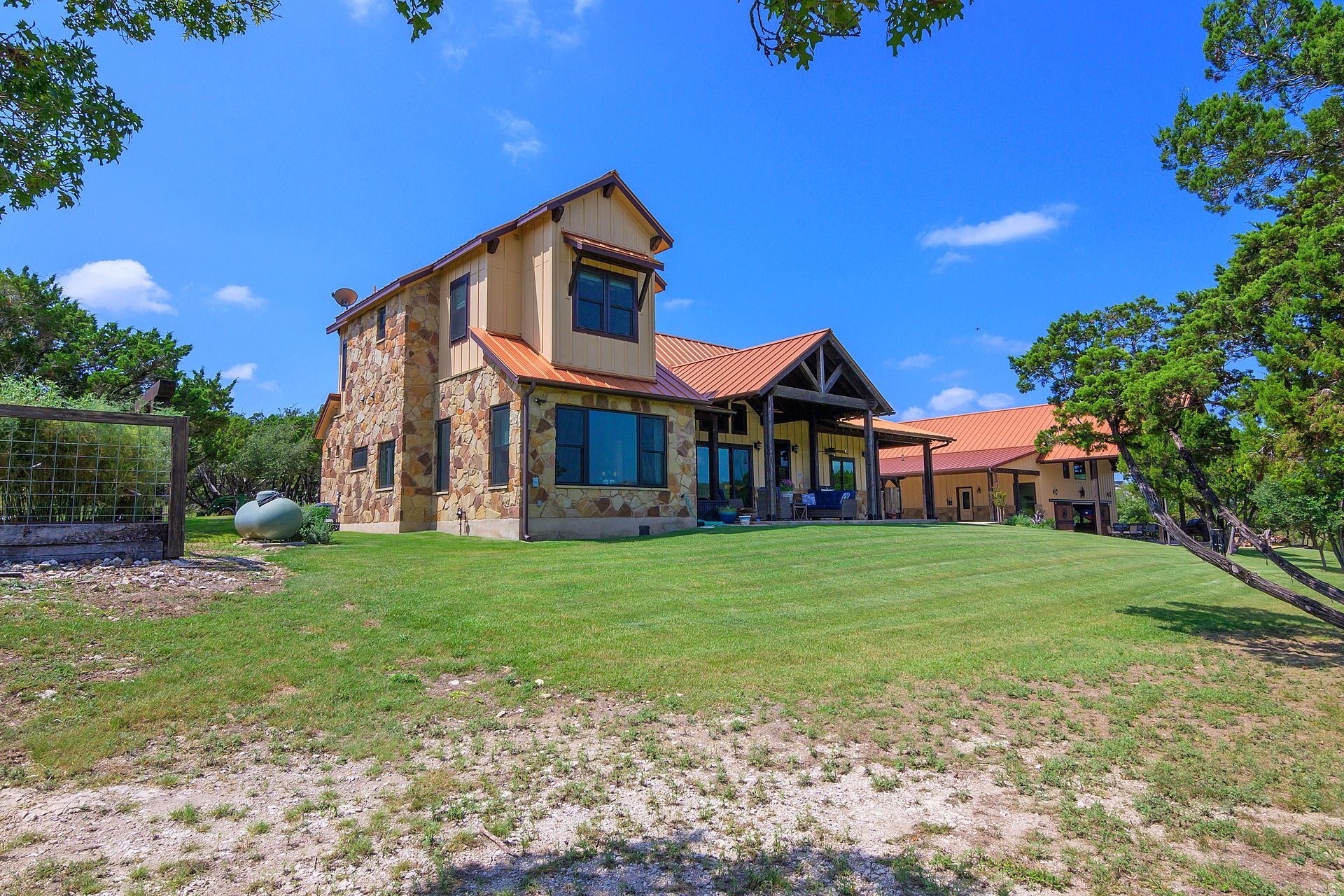 A large house with a red tile roof is sitting in the middle of a lush green field.