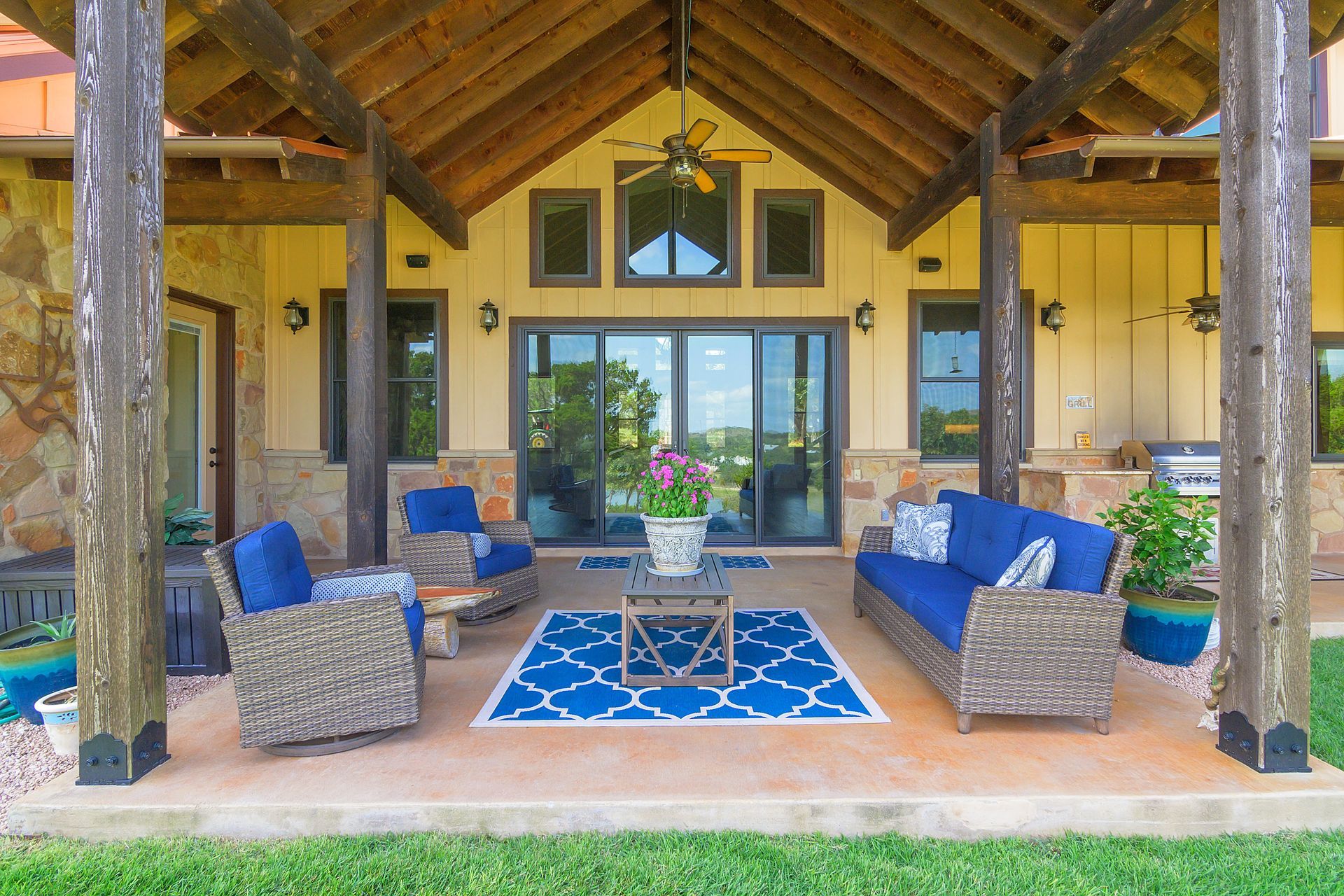 A patio with a couch , chairs , and a blue rug.