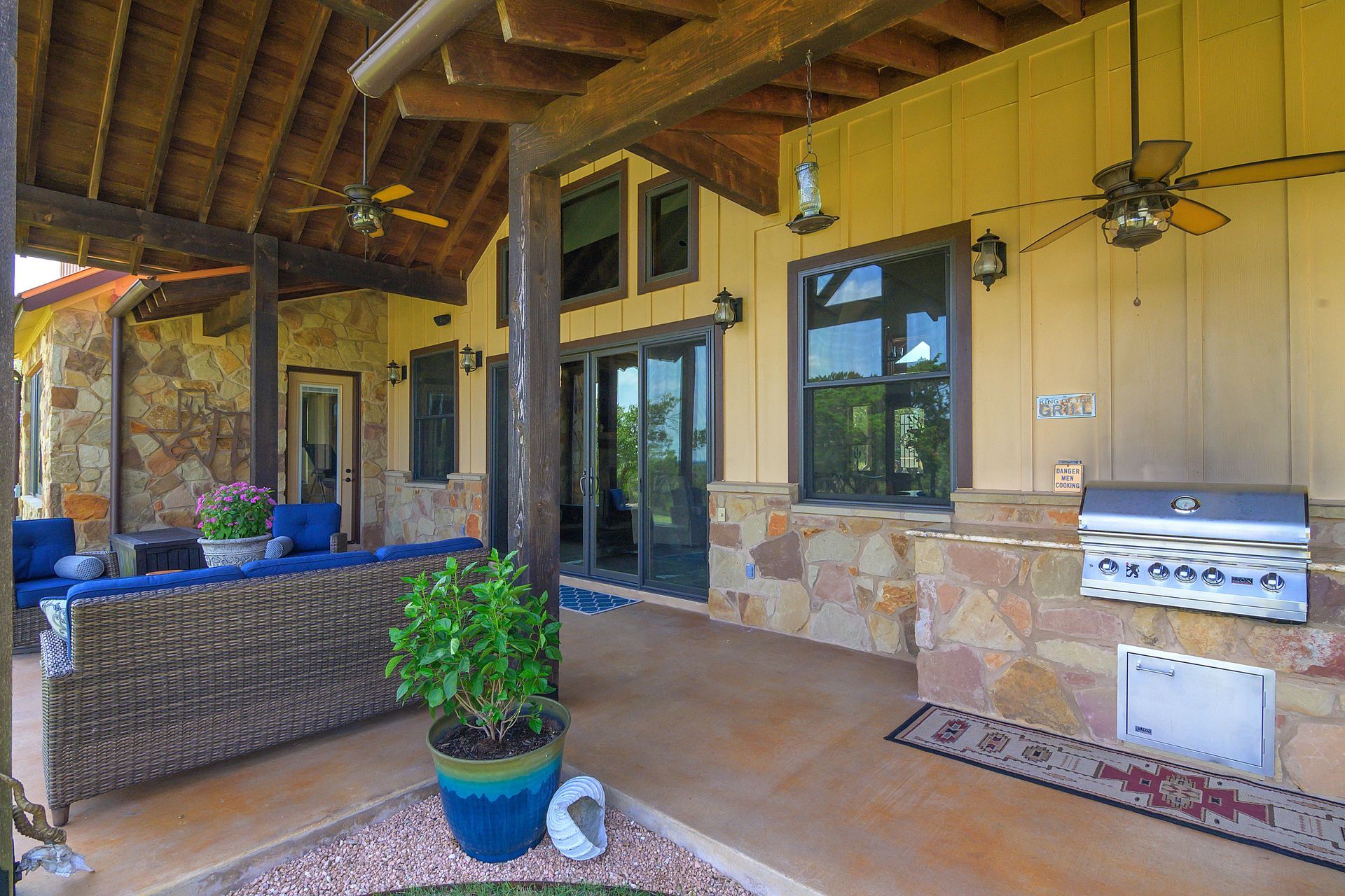 A large patio with a ceiling fan and a grill.