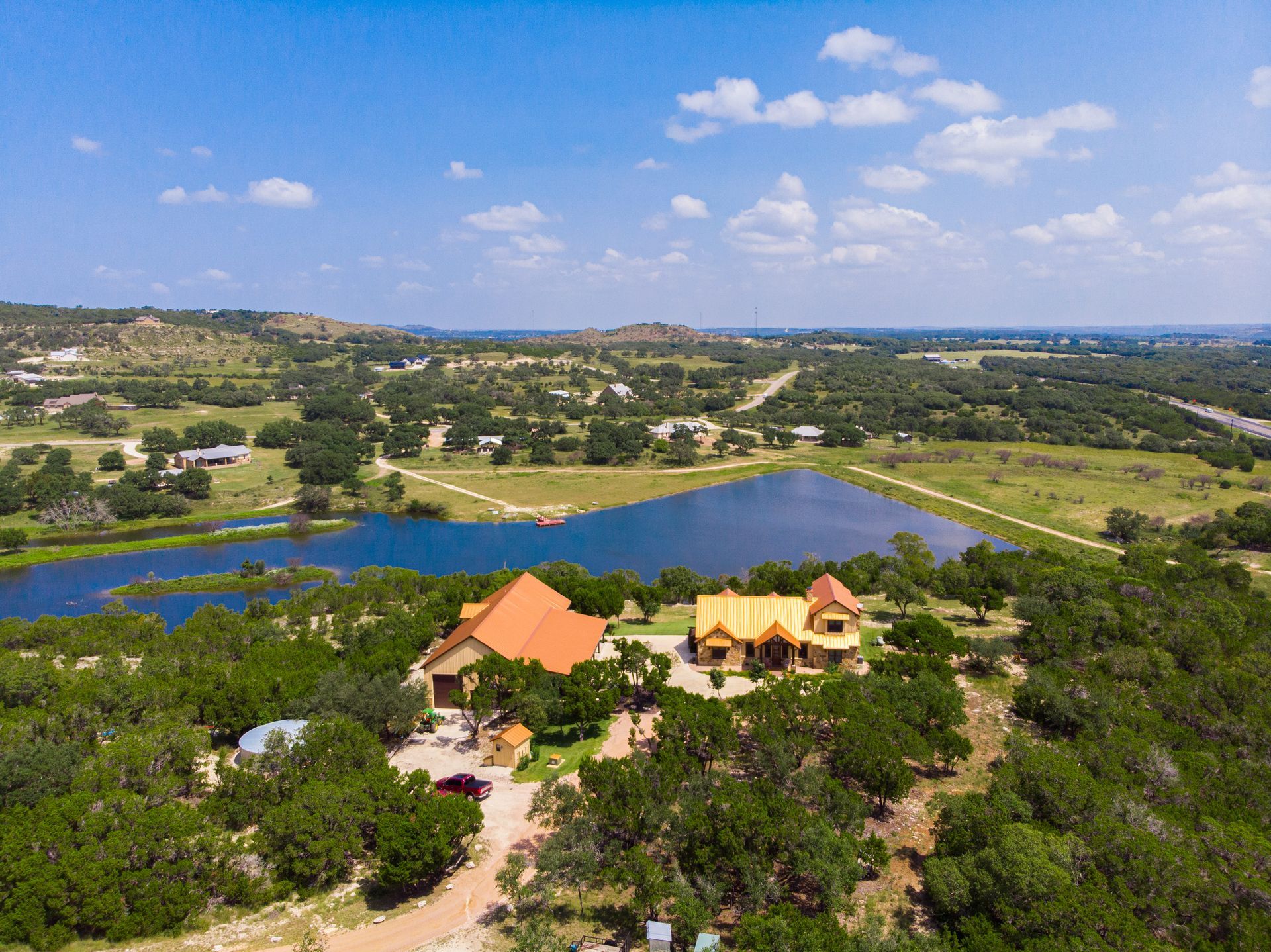 An aerial view of a house surrounded by trees and a lake.