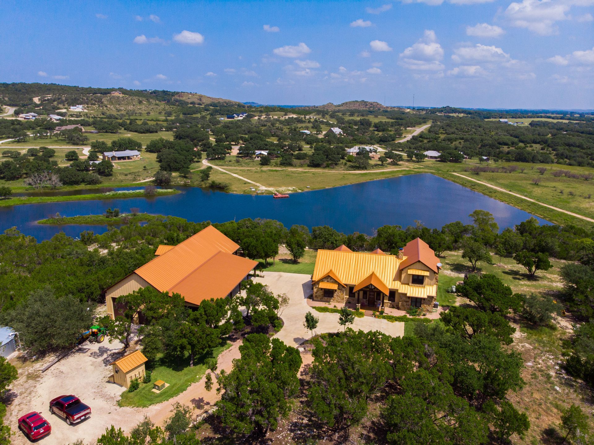 An aerial view of a large house surrounded by trees and a lake.