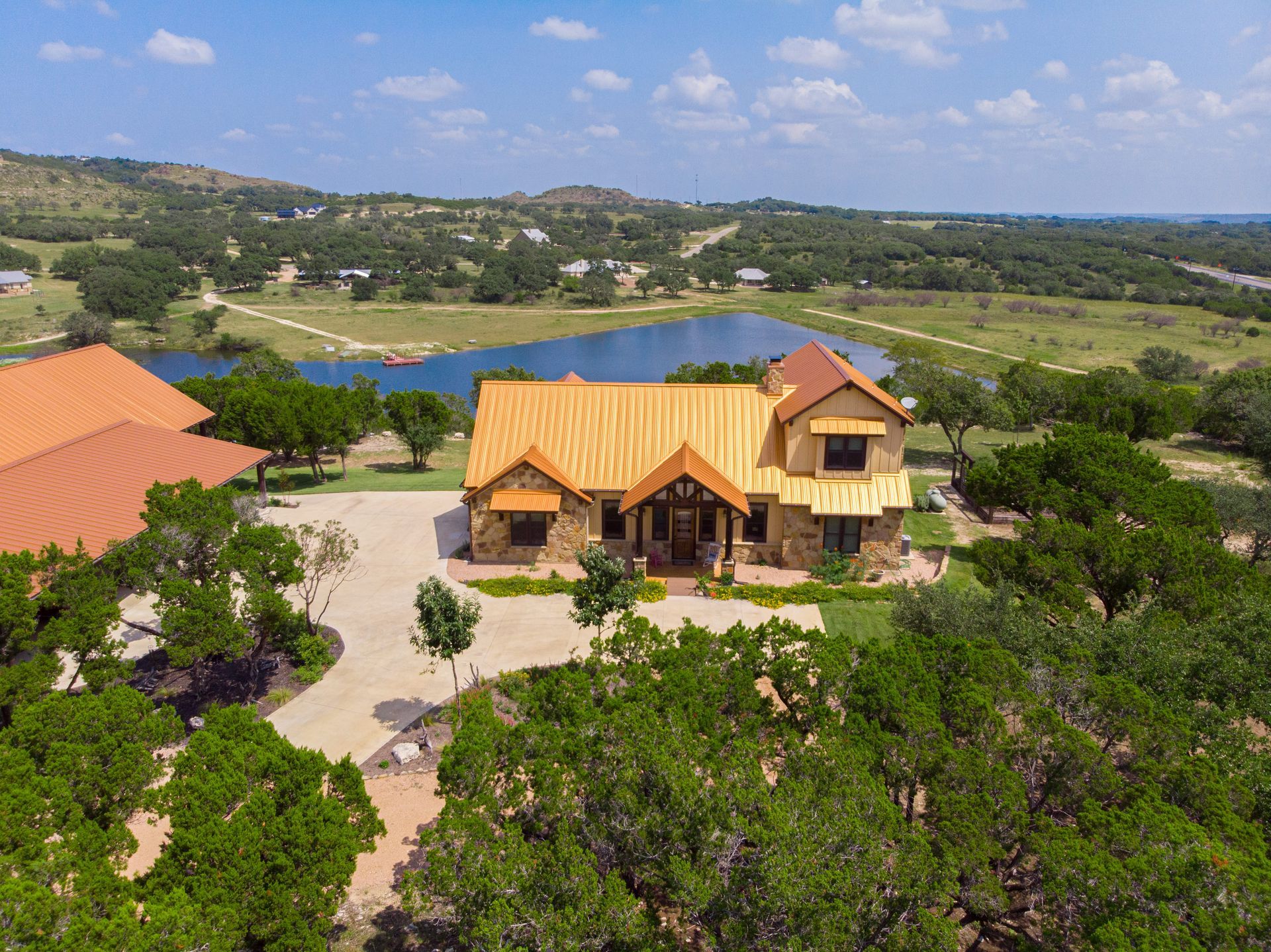 An aerial view of a large house surrounded by trees and a lake.