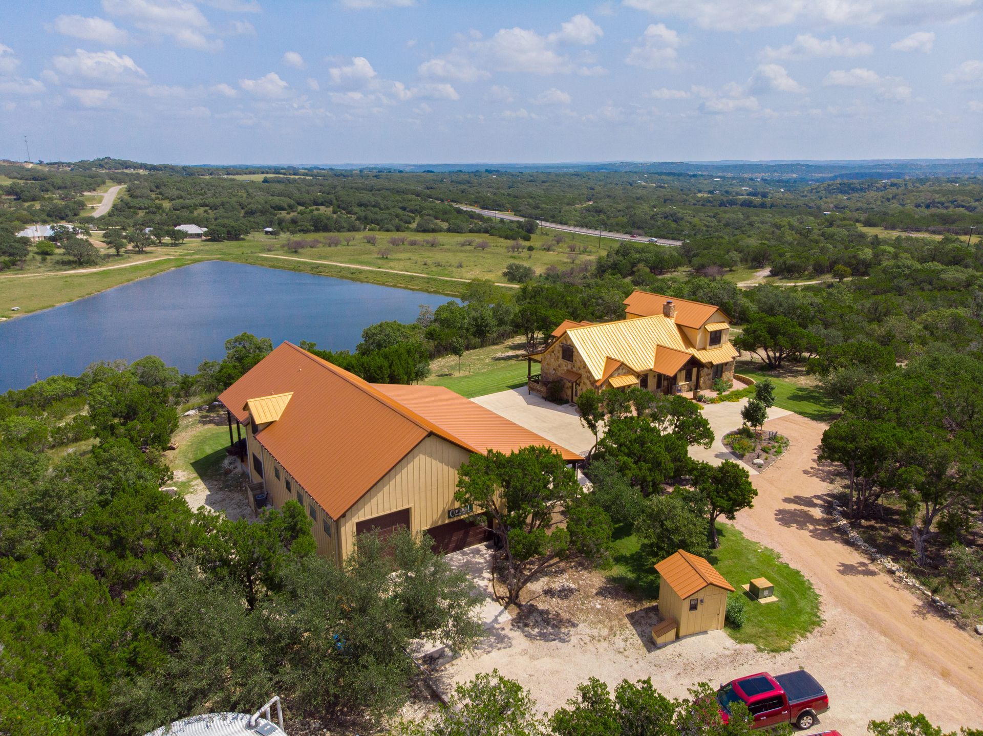 An aerial view of a large house surrounded by trees and a lake.