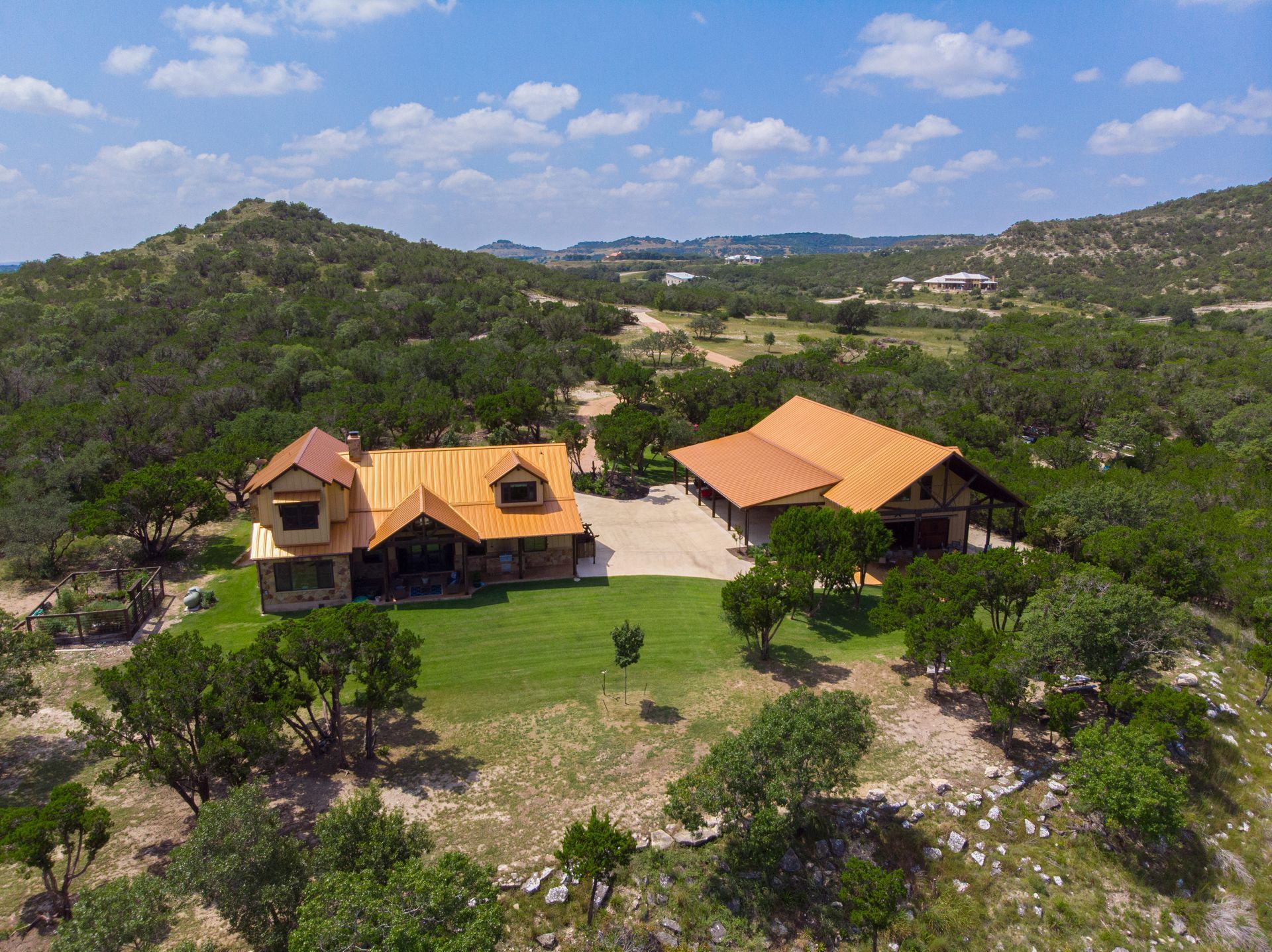 An aerial view of a large house on top of a hill surrounded by trees.