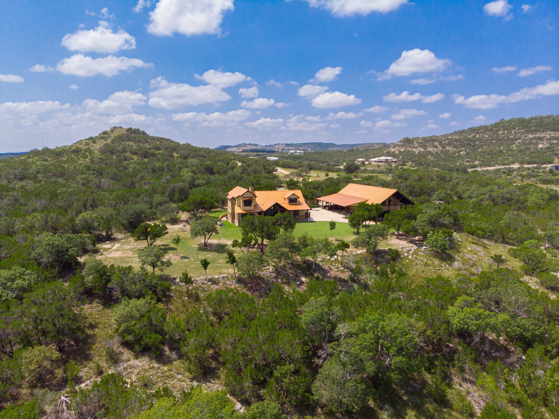 An aerial view of a house on top of a hill surrounded by trees.