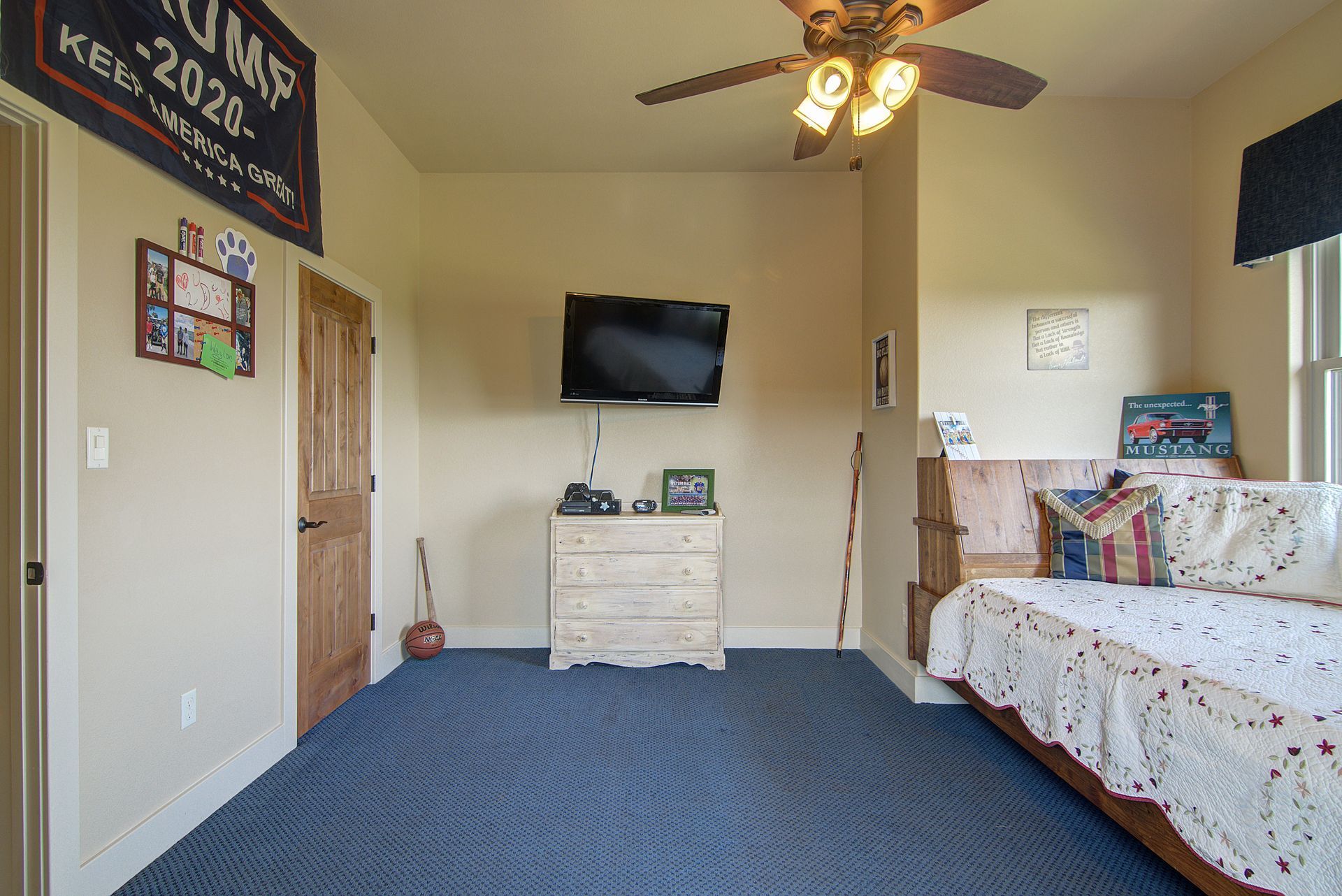 A bedroom with a bed , dresser , television and ceiling fan.