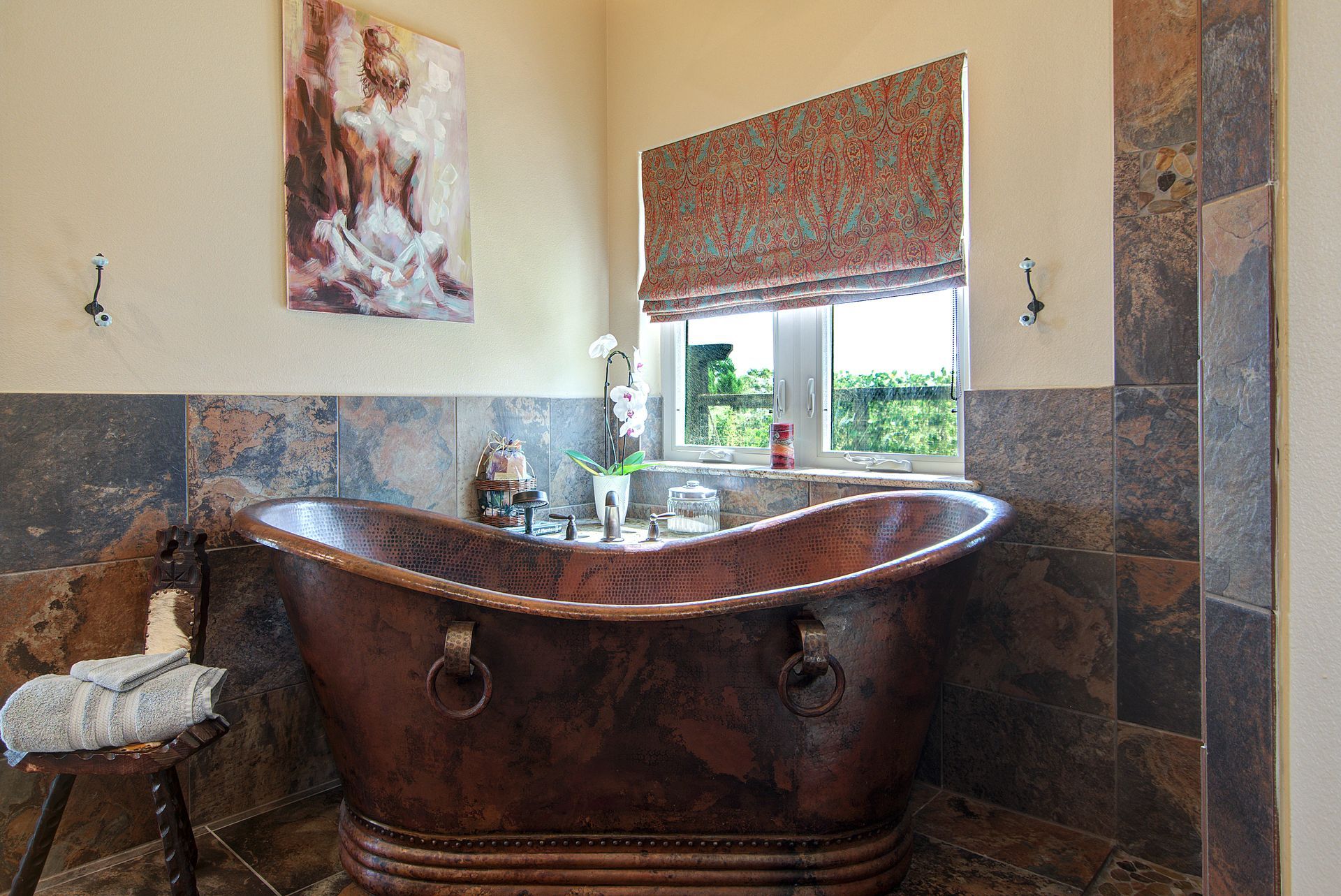 A copper bathtub is in a bathroom next to a window.