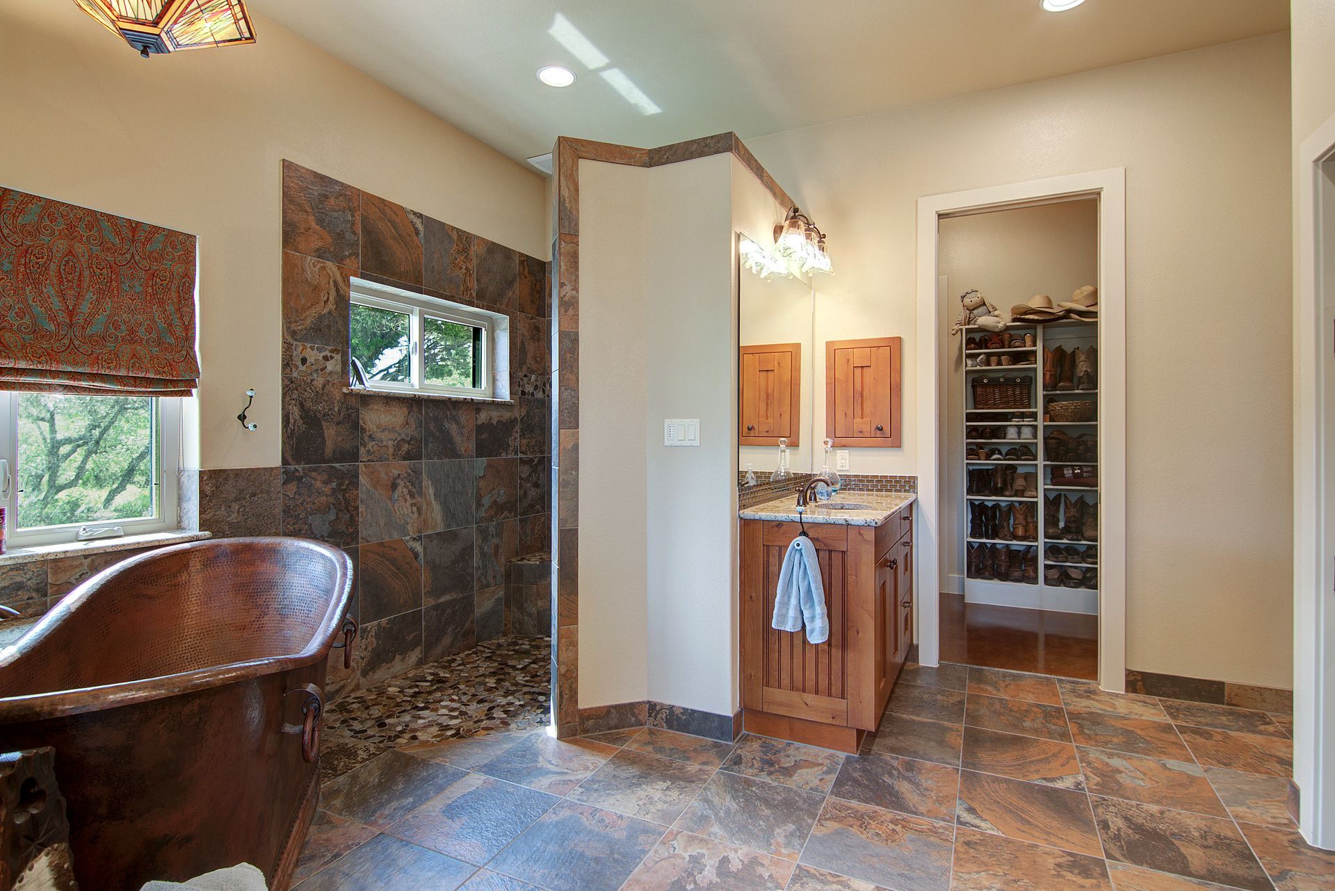 A bathroom with a copper tub , sink , and walk in shower.
