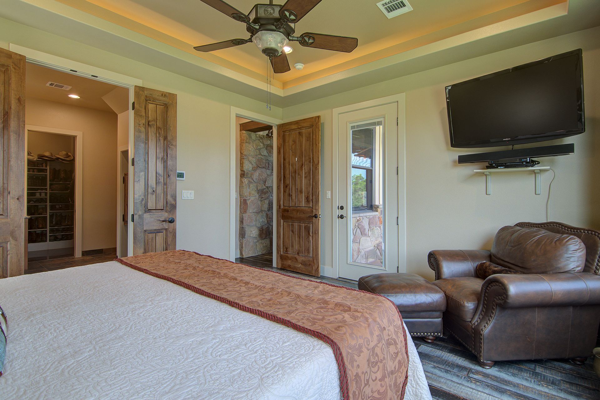 A bedroom with a bed , chair , television and ceiling fan.
