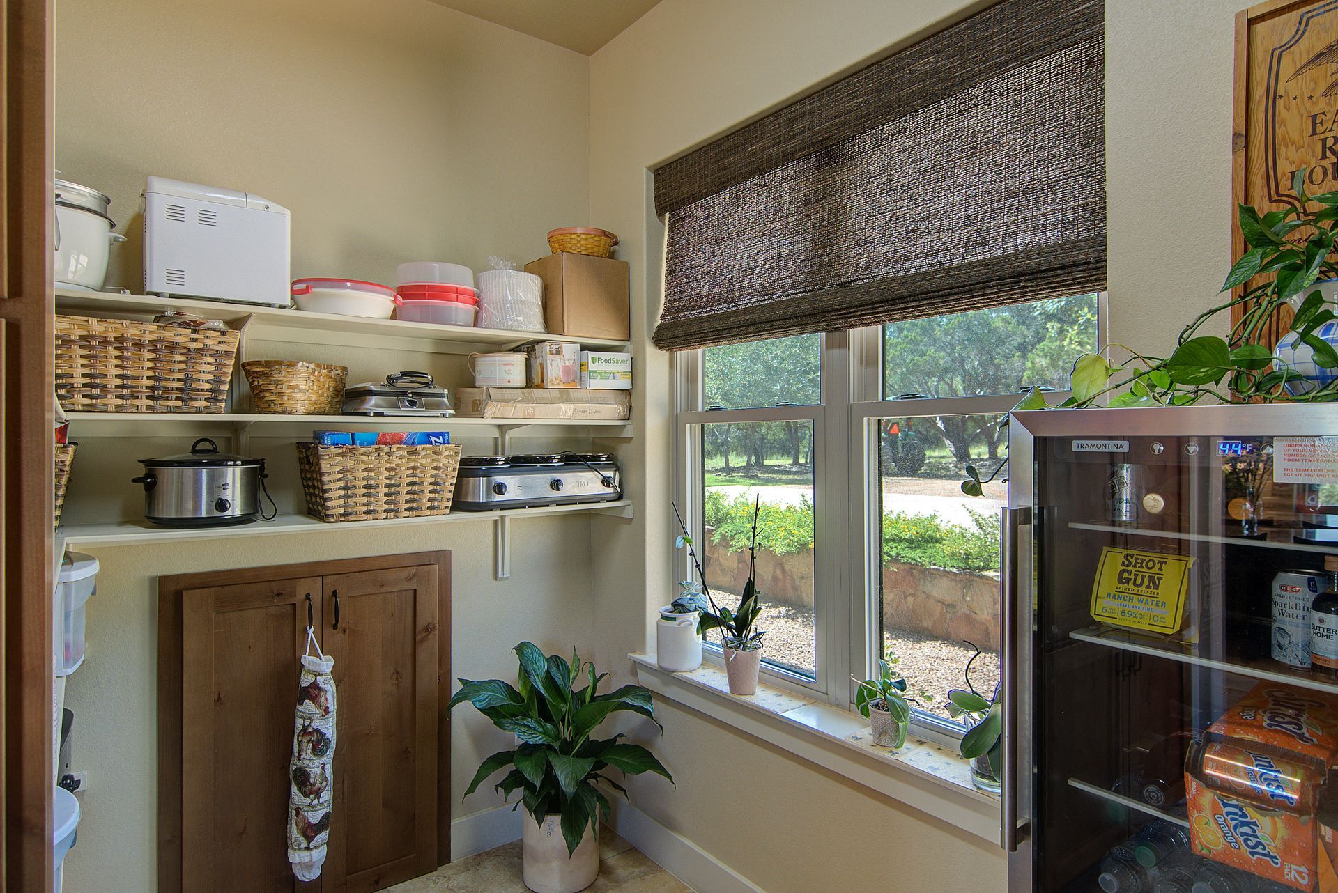 A pantry with shelves , a refrigerator and a window.