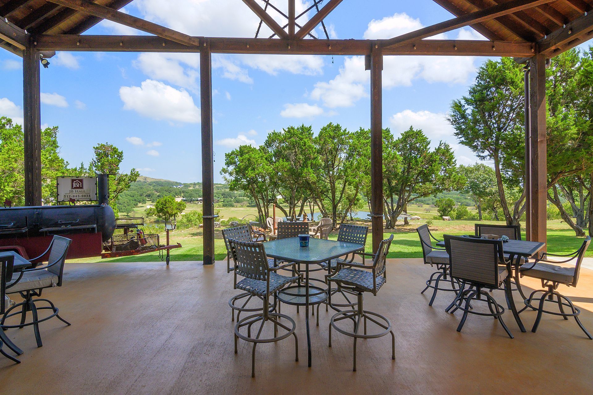 A covered patio with tables and chairs and a grill.