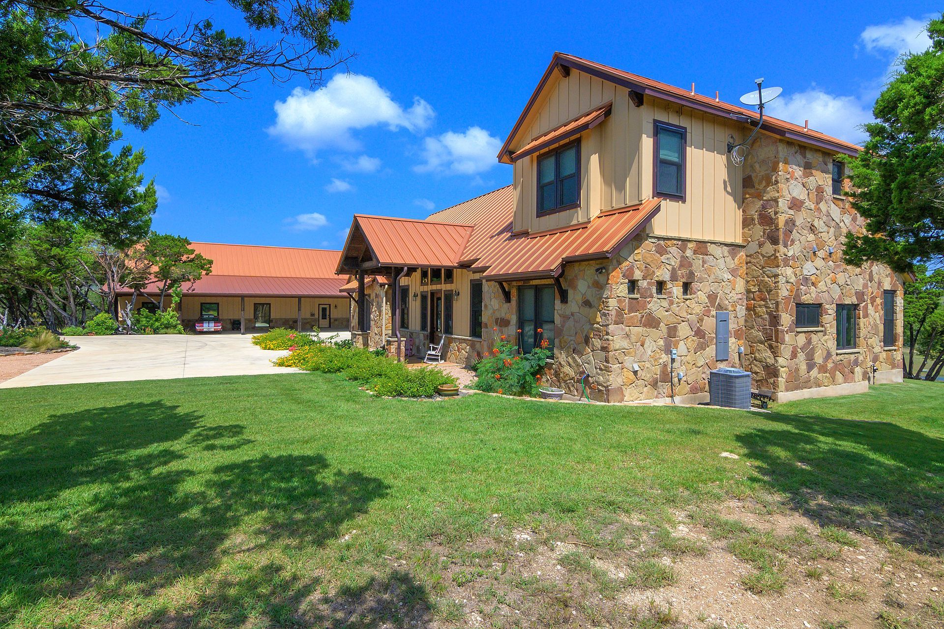 A large stone house with a red tile roof is sitting on top of a lush green field.