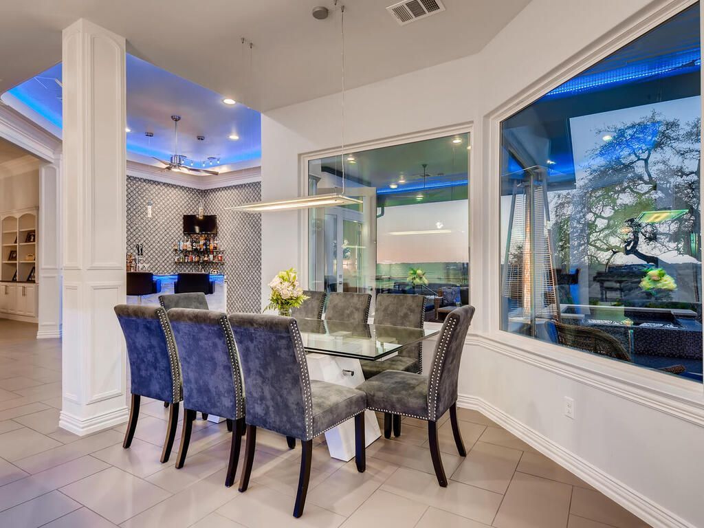 A dining room with a table and chairs and a large window.