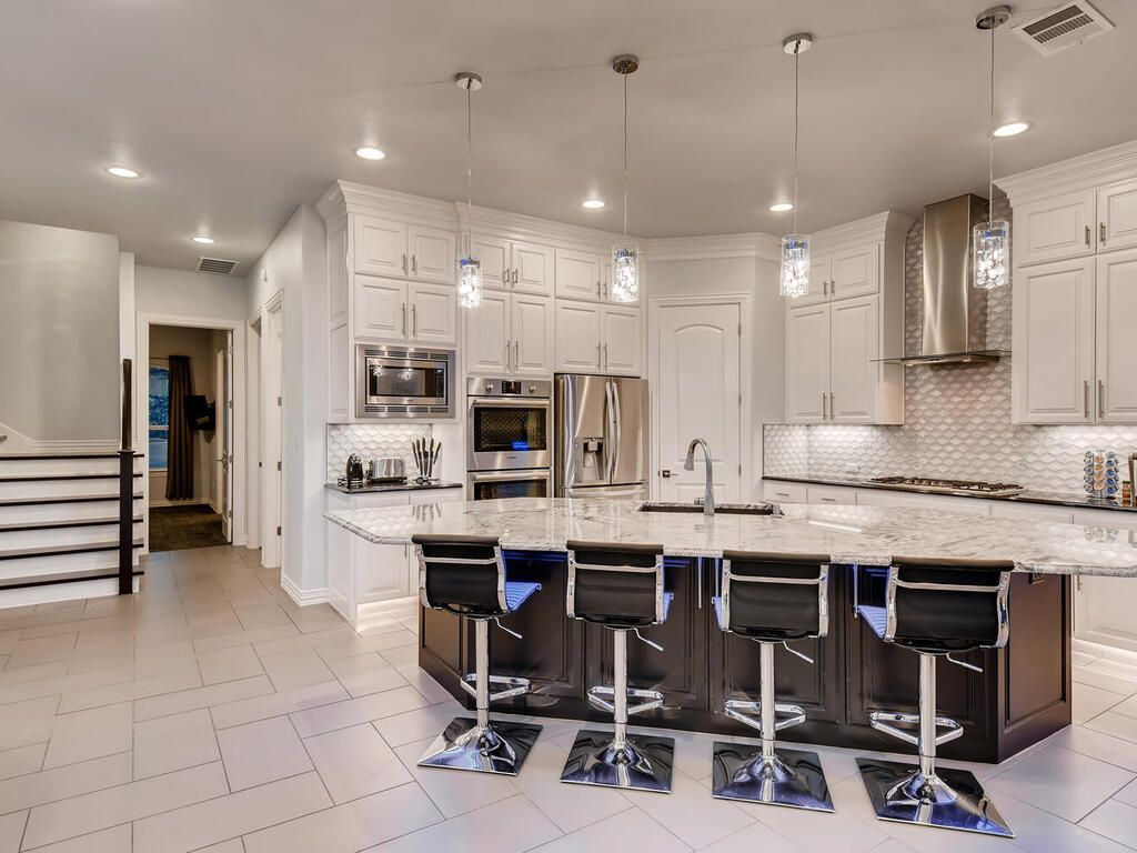 A kitchen with white cabinets , granite counter tops , stainless steel appliances and a large island.